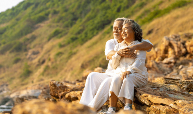 Older man and woman sitting on a cliff in nature